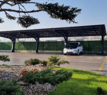 Ein E-Auto steht unter einem Solarcarport und wird geladen